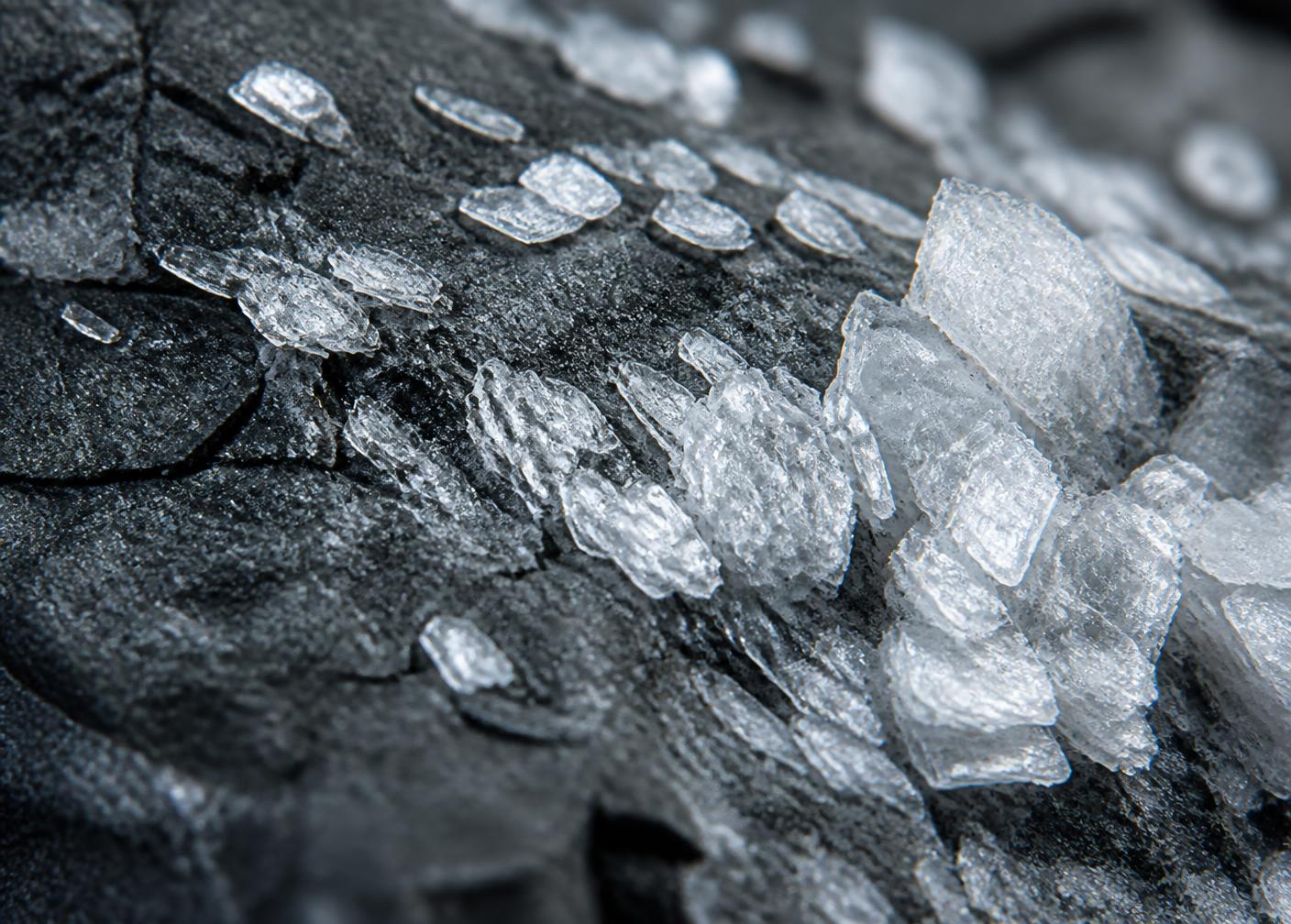 Macro view of white crystalline mineral flakes on dark stone