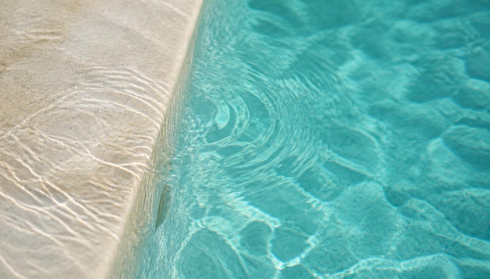 Clear pool water meeting a pale stone step